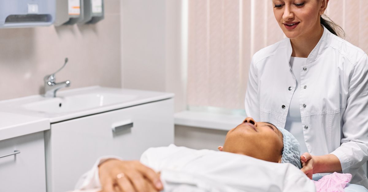 A beautician providing skincare treatment to a woman in a clinic setting, focusing on care and relaxation.